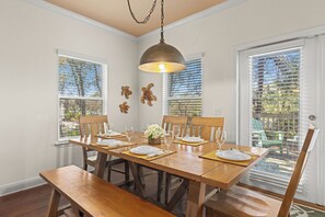 Una sala da pranzo con un tavolo in legno apparecchiato per sei persone, una lampada a sospensione e decorazioni a parete.