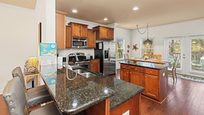 A kitchen with granite countertops, stainless steel appliances, wooden cabinets, and a large island. - The Winking Turtle – Your Shell-tered Beach Escape! Sleeps 10! (Inlet Beach)