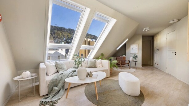 Un moderno loft con soffitto spiovente, ampie finestre, un divano, un tavolino da caffè e un piccolo angolo pranzo.