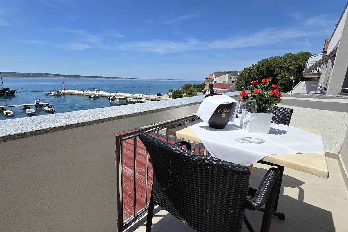 Un balcon avec une table, des chaises, un verre à vin et une bouteille de vin.