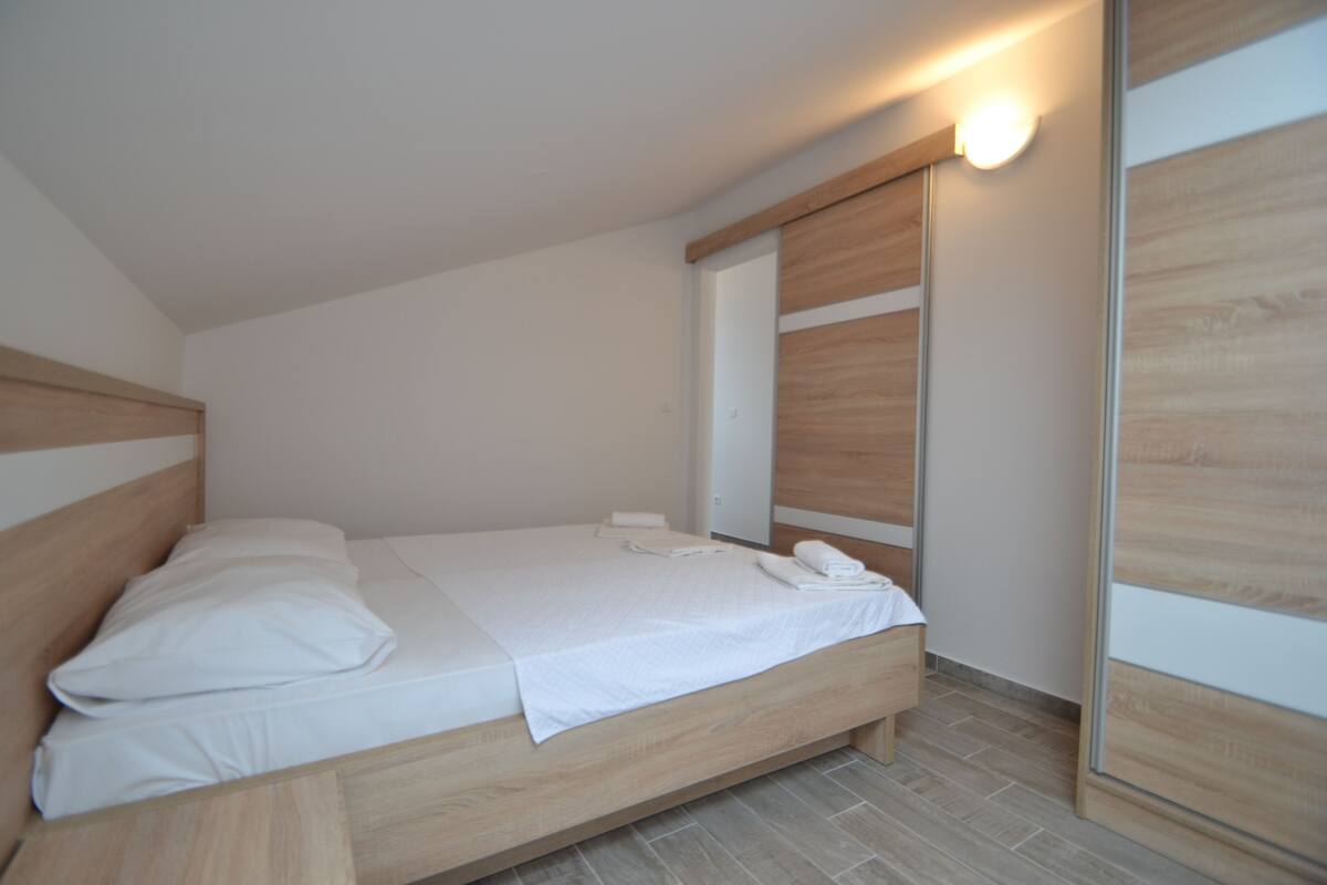 Une chambre moderne avec un cadre de lit en bois, du linge de lit blanc et une armoire intégrée.