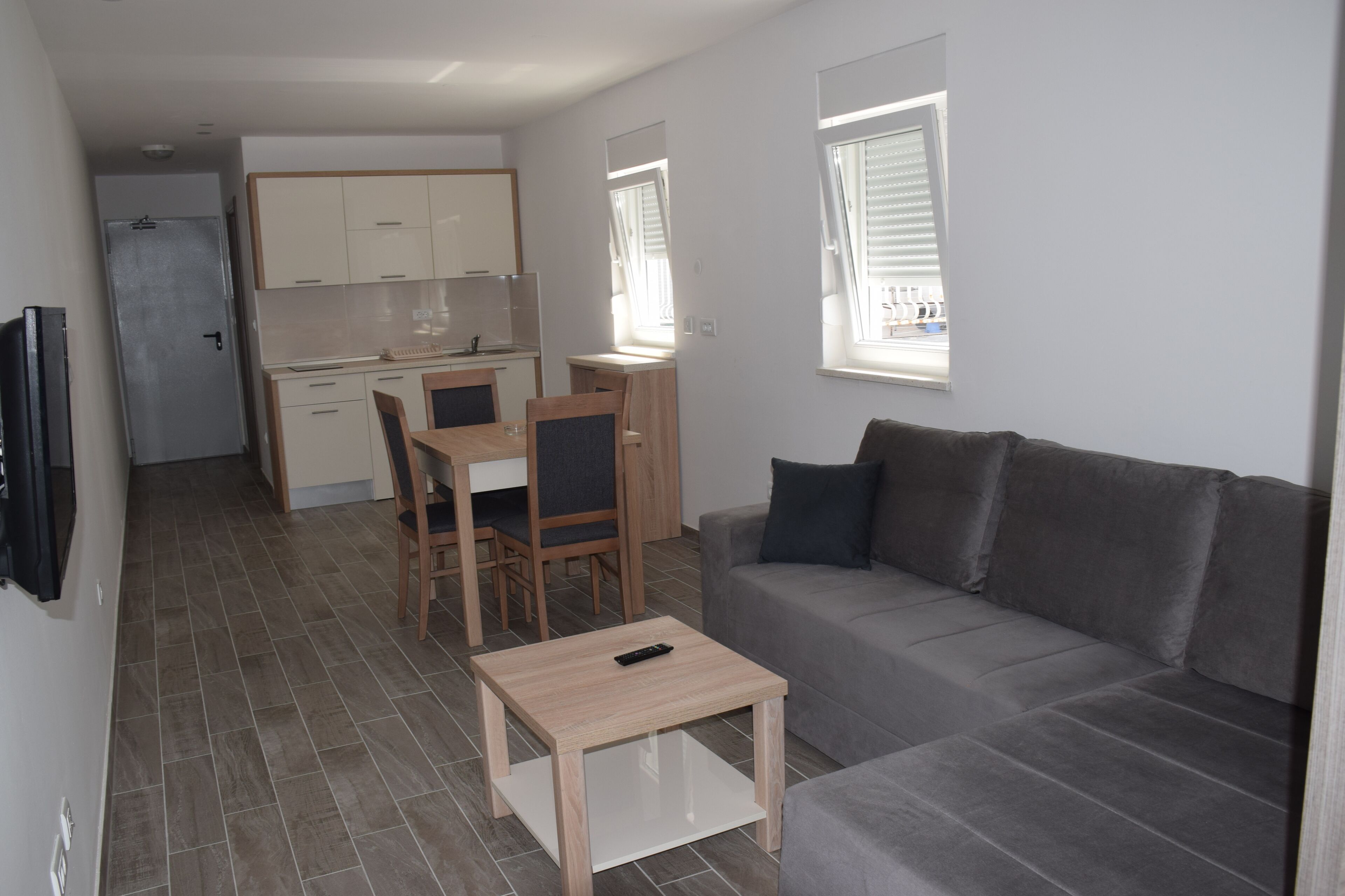 Un espacio habitable compacto con kitchenette, sofá, mesa de centro y televisión.