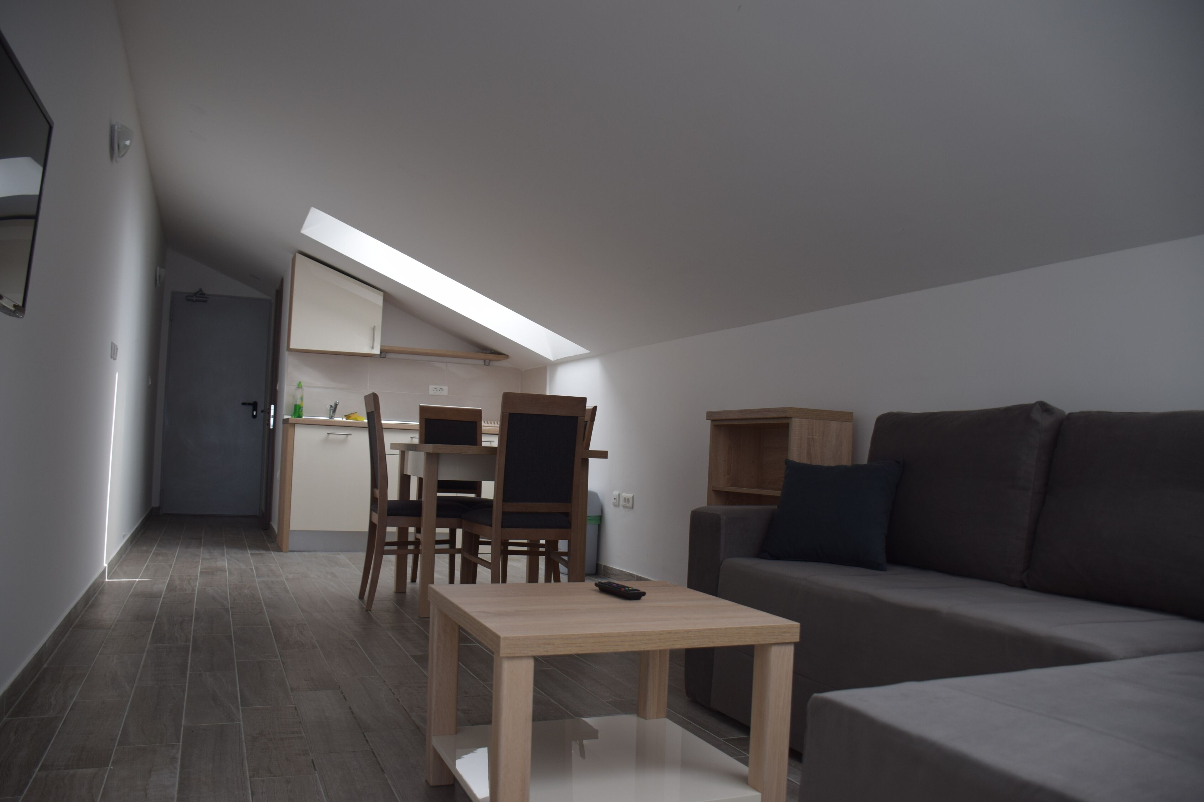 A modern, compact living space with a dining area, a sofa, and a small table.
