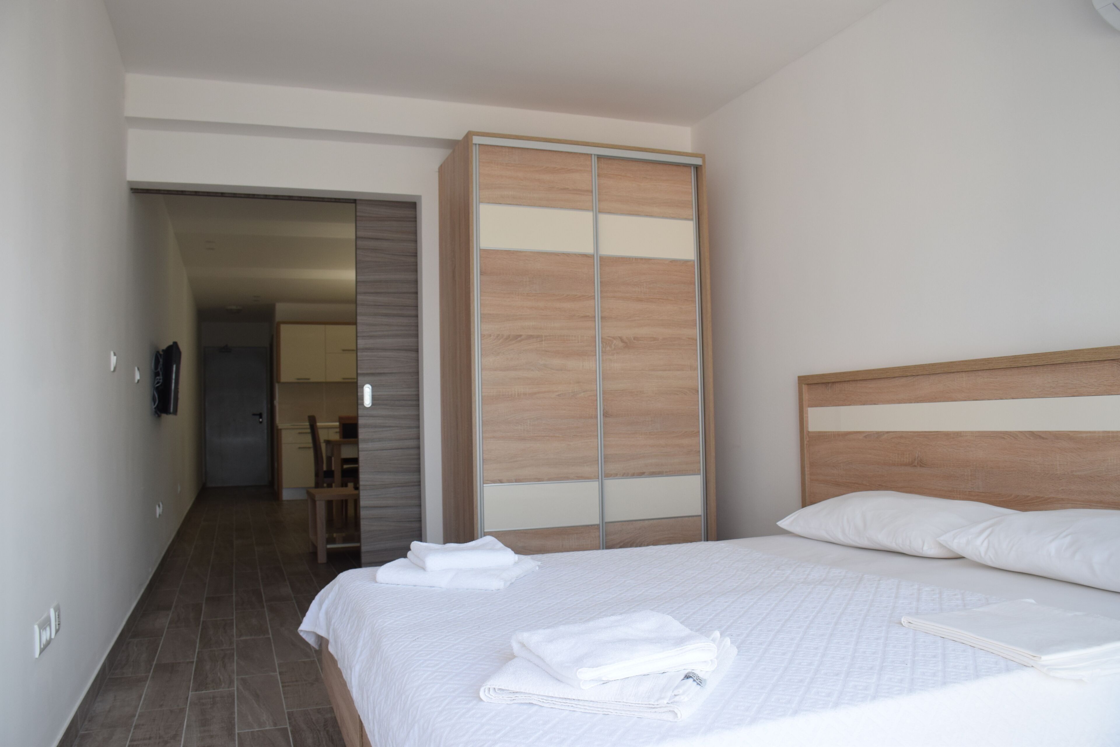 Una habitación de hotel con cama, armario de madera, baño y pasillo.