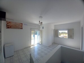 A spacious room with a marble floor, a ceiling fan, a sliding glass door, and a window with a view.