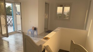 A room with a marble floor, a small blue stool, a white table, and a window with a view of buildings.
