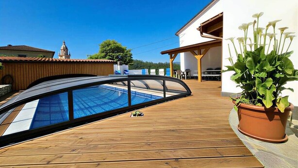 En træterrasse med swimmingpool, en plantekasse og en bygning med tegltag.