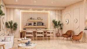 A modern living room with a dining area, featuring a sofa, coffee table, chairs, and a kitchen island with built-in lighting. - Palette Hotel & Convention Centre (Gurugram)