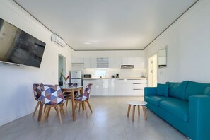 Ein modernes Wohnzimmer mit Küche, Essbereich und einem türkisfarbenen Sofa.