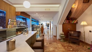 Una zona de bar con asientos, una máquina de café y una estantería.