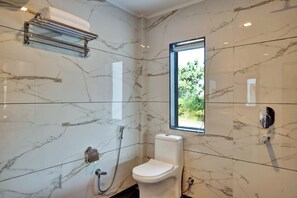 A bathroom with a toilet, a shower, a towel rack, and a window.