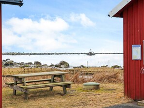 Een rood gebouw met een picknicktafel en een kleine groene bak in de buurt.