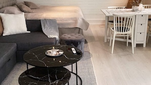 A modern living room with a sofa, a round coffee table, a dining table with chairs, and a painting on the wall. - 4 Person Holiday Home in Tvaaker (Tvaaker)