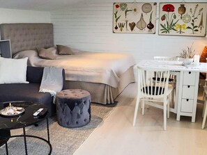 Ein gemütliches Zimmer mit einem Bett, einem Esstisch und einem kleinen Hocker.
