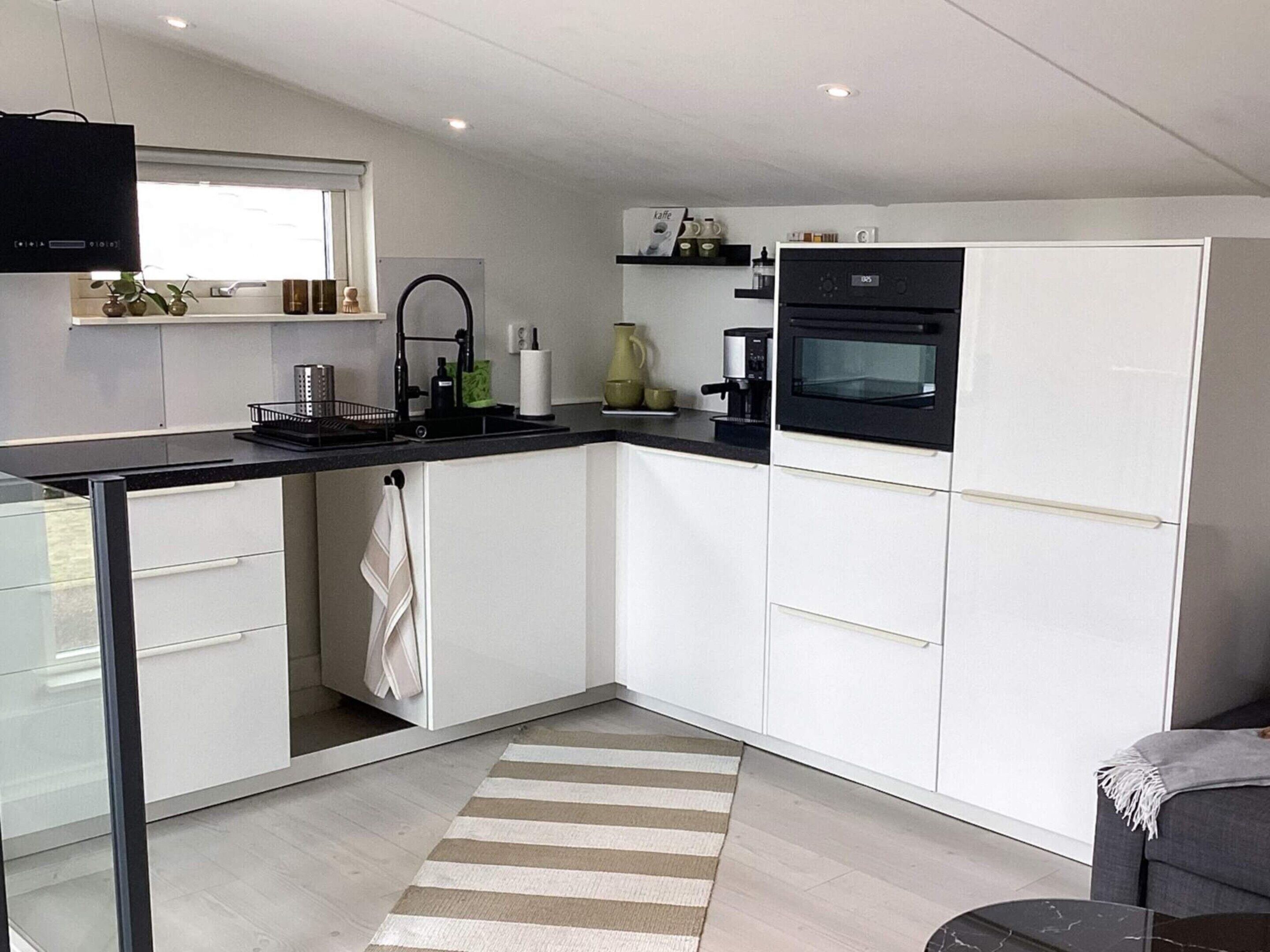 Een moderne keuken met witte kasten, een zwart aanrecht, een koffieapparaat en een magnetron.