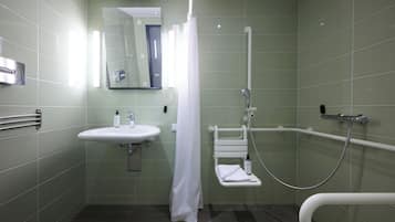 A bathroom with a sink, mirror, shower, and grab bar.