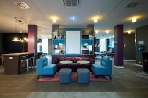 Un espace de détente moderne comprenant un canapé, des poufs, un bar et une grande fenêtre.