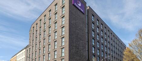 Un moderno edificio de hotel con un llamativo rótulo de Premier Inn, varios pisos y fachada de ladrillo.