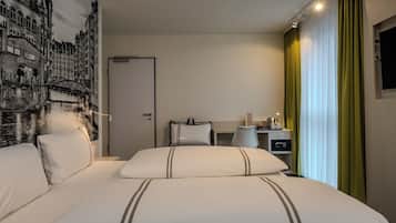 A hotel room with a large bed, a nightstand with a lamp, a wall-mounted TV, and a door.