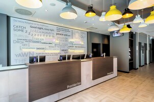 Ein Hotelrezeptionstresen mit modernem Design, der ein Holzbühne und einen digitalen Bildschirm zeigt.