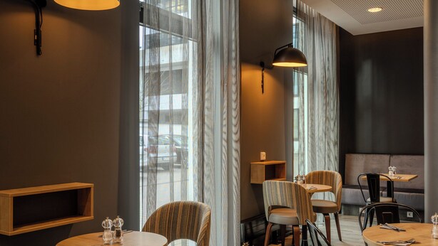 A modern dining area with round tables, chairs, and pendant lighting.