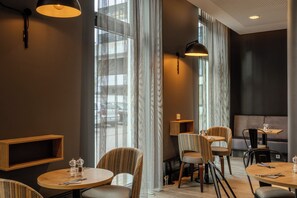 Un comedor moderno con mesas redondas, sillas e iluminación colgante.