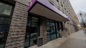 A brick building with large windows and a purple awning.