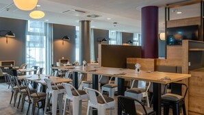A modern conference room with a long table, multiple chairs, and pendant lighting.