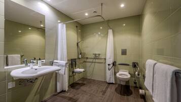 A bathroom with a sink, toilet, shower, and grab bars.
