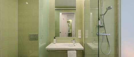 Un baño moderno con ducha envuelta en vidrio, un lavabo blanco y un inodoro.