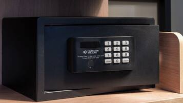 A black safe with a keypad, labeled 'HARTMANN TREASURE,' on a wooden shelf.
