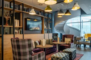 A modern interior with a curved staircase, seating areas, and pendant lighting. - Premier Inn Koblenz City (Koblenz)