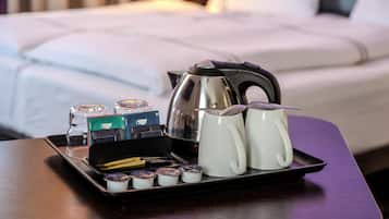 Sur une table dans une chambre d’hôtel, on trouve un plateau avec des sachets de thé, une bouilloire et deux tasses.