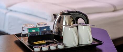 Una bandeja con bolsitas de té, un hervidor y dos tazas sobre una mesa en una habitación de hotel.