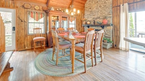 A wooden dining table with chairs, a chandelier, a stone wall, and a wooden ceiling. - Almond Family Retreat (Almond)