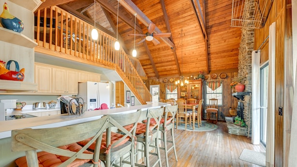A rustic kitchen with wooden bar stools, a wooden ceiling, and a stone wall. - Almond Family Retreat (Almond)