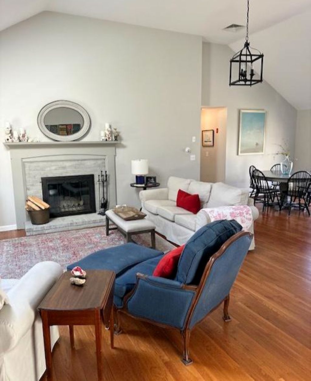 A living room with a fireplace, a sofa, a chair, a dining table, and a chandelier.