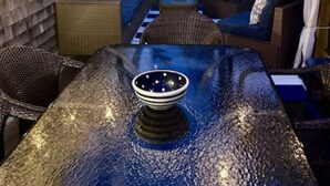 An outdoor patio with a glass-top table, wicker furniture, and string lights. - Short Drive to Red River Beach (Harwich)