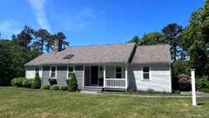 A single-story house with a front porch, a chimney, and a well-maintained lawn. - Short Drive to Red River Beach (Harwich)