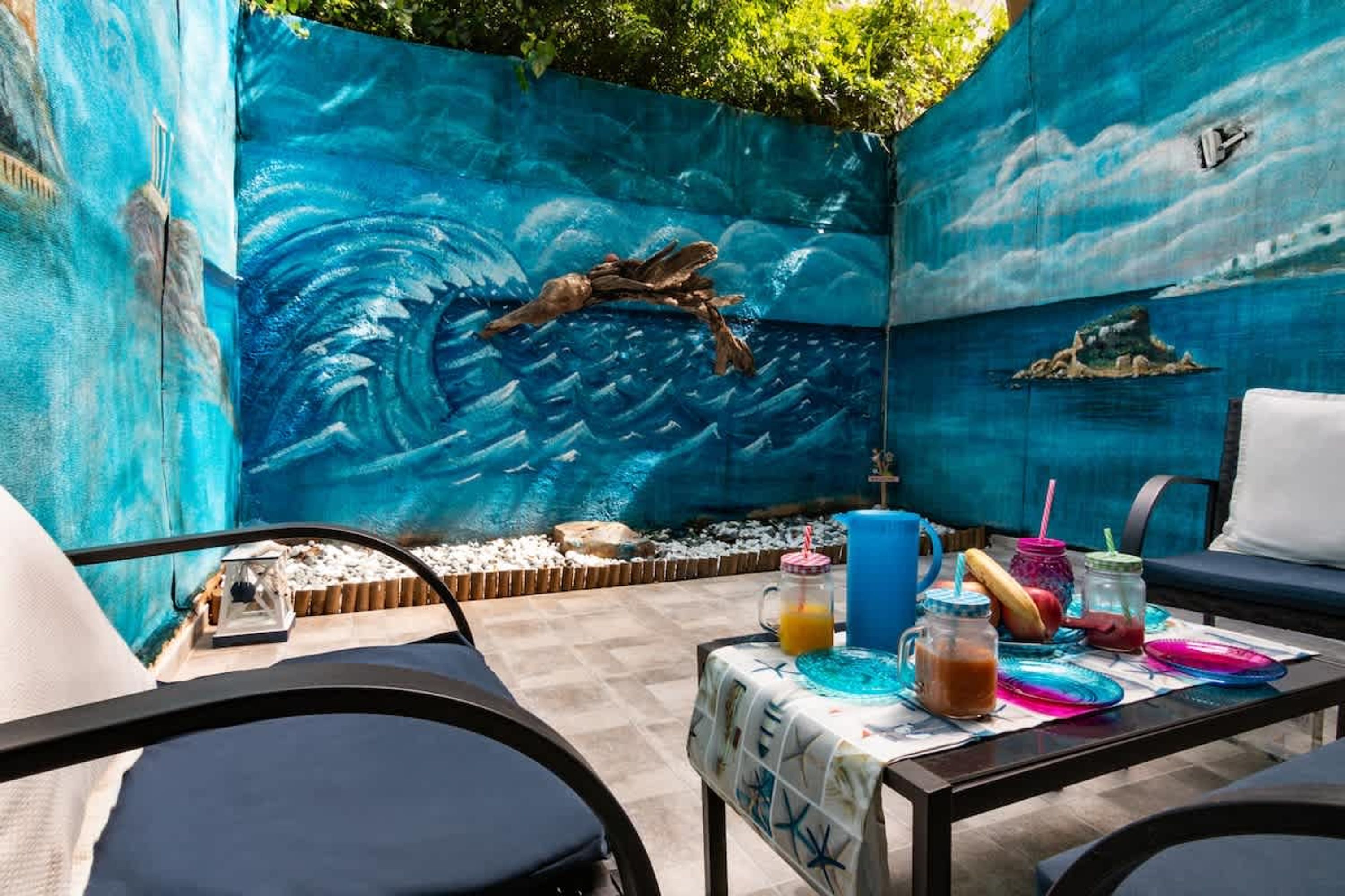 A poolside area with a mural, a table with drinks, and lounge chairs.