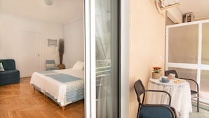 A bedroom with a bed, a sofa, a table with chairs, and a sliding glass door leading to a balcony. - Seaside Escape With Balcony in Paleo Faliro (Palaio Faliro)