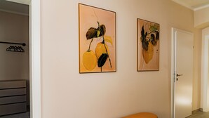 Un corridoio con due quadri appesi al muro, una panca e una porta.