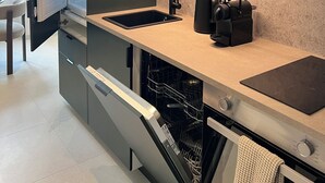 Una cucina moderna con lavastoviglie, lavello e macchina da caffè sul piano di lavoro.