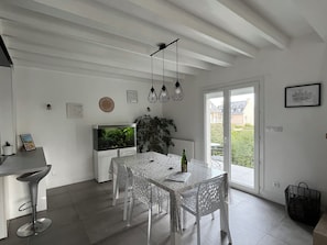 Una cocina moderna con comedor, muebles blancos, un acuario grande y vistas al exterior.