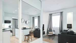A modern apartment with a kitchen, dining area, and living room, featuring a large mirror, grey curtains, and a welcome sign. - Modernized 1920s Apartment (Turku)