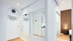 A modern interior with a mirrored closet, a clock, and a wooden panel wall. - Modernized 1920s Apartment (Turku)