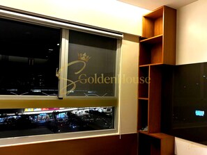 A room with a large window, a wooden shelf unit, and a flat-screen TV. - Scenic Valley 2 EmHouse (Ho Chi Minh City)