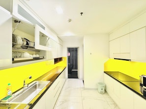 Una cocina moderna con una pared de acento amarilla, un lavamanos de acero inoxidable y una encimera negra.