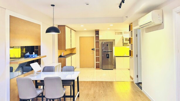 Una cocina moderna con comedor, armarios de madera, horno empotrado y refrigerador.