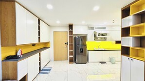 Una cocina moderna con armarios blancos, un refrigerador de acero inoxidable y una encimera amarilla.